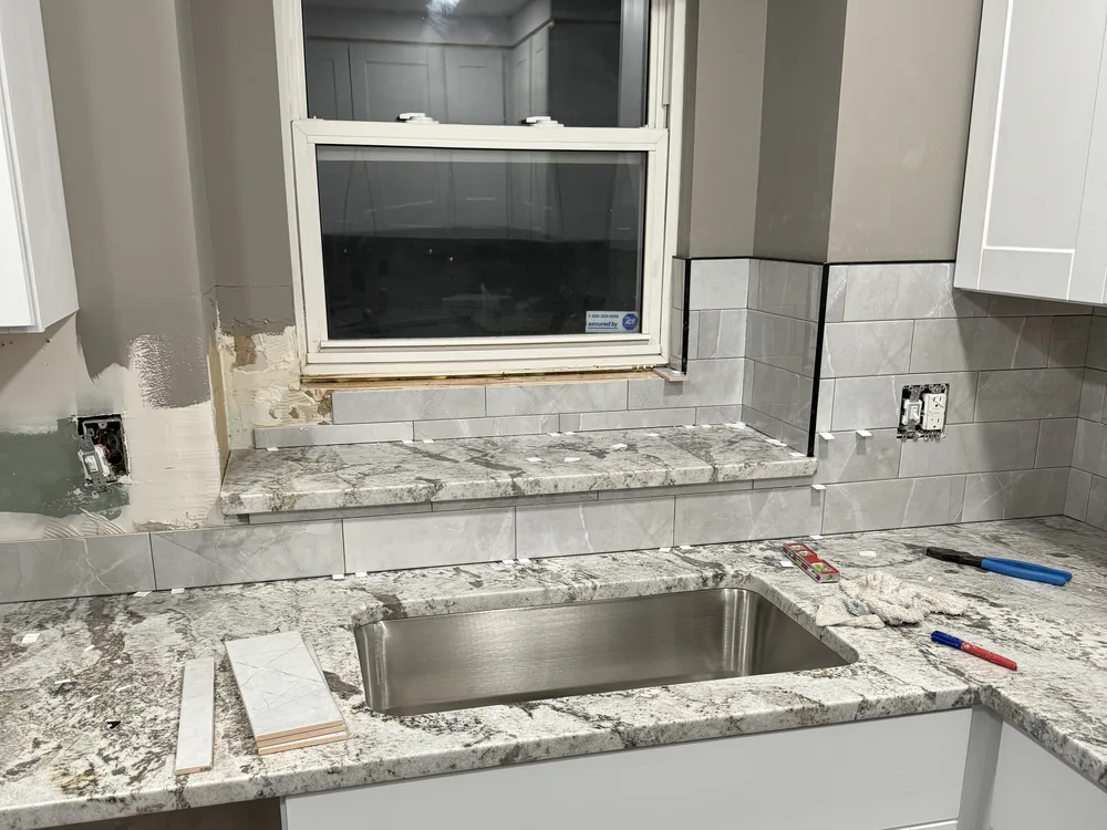 Kitchen remodel in Blue Springs, MO — backsplash tile and granite countertop installation over the sink