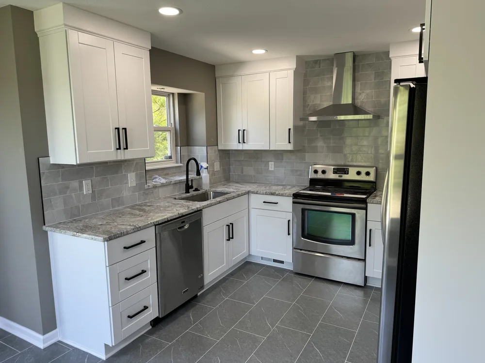 Kitchen remodel in Blue Springs, MO with white shaker cabinetry, gray subway tile backsplash, and granite countertops