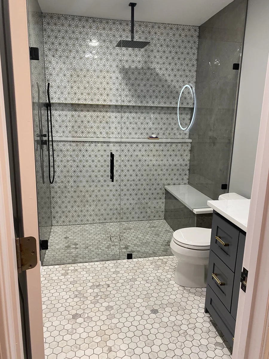 Finished bathroom remodel in Kansas City, MO with marble star-pattern tile accent wall, zero-entry shower, built-in bench, and custom vanity