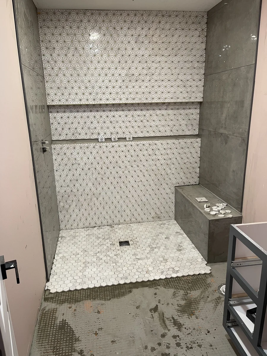 Bathroom remodel in Kansas City, MO — marble star-pattern accent wall tile and hexagon shower floor tile being installed