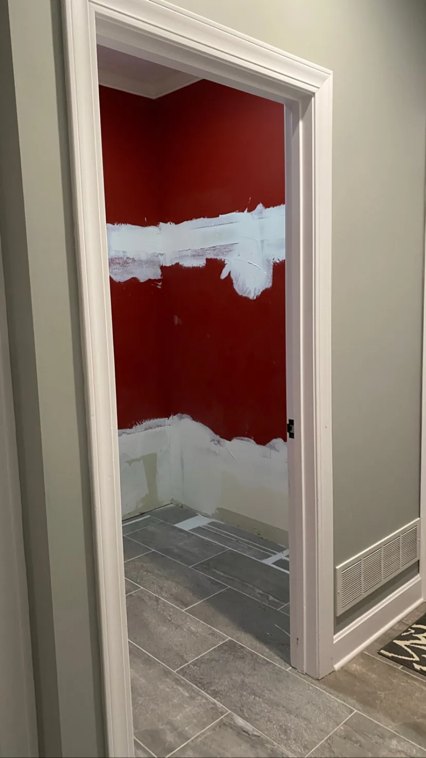 Mudroom remodel in Kansas City, MO before work: the original room closed off behind a standard door, with dark red walls seen from the hall