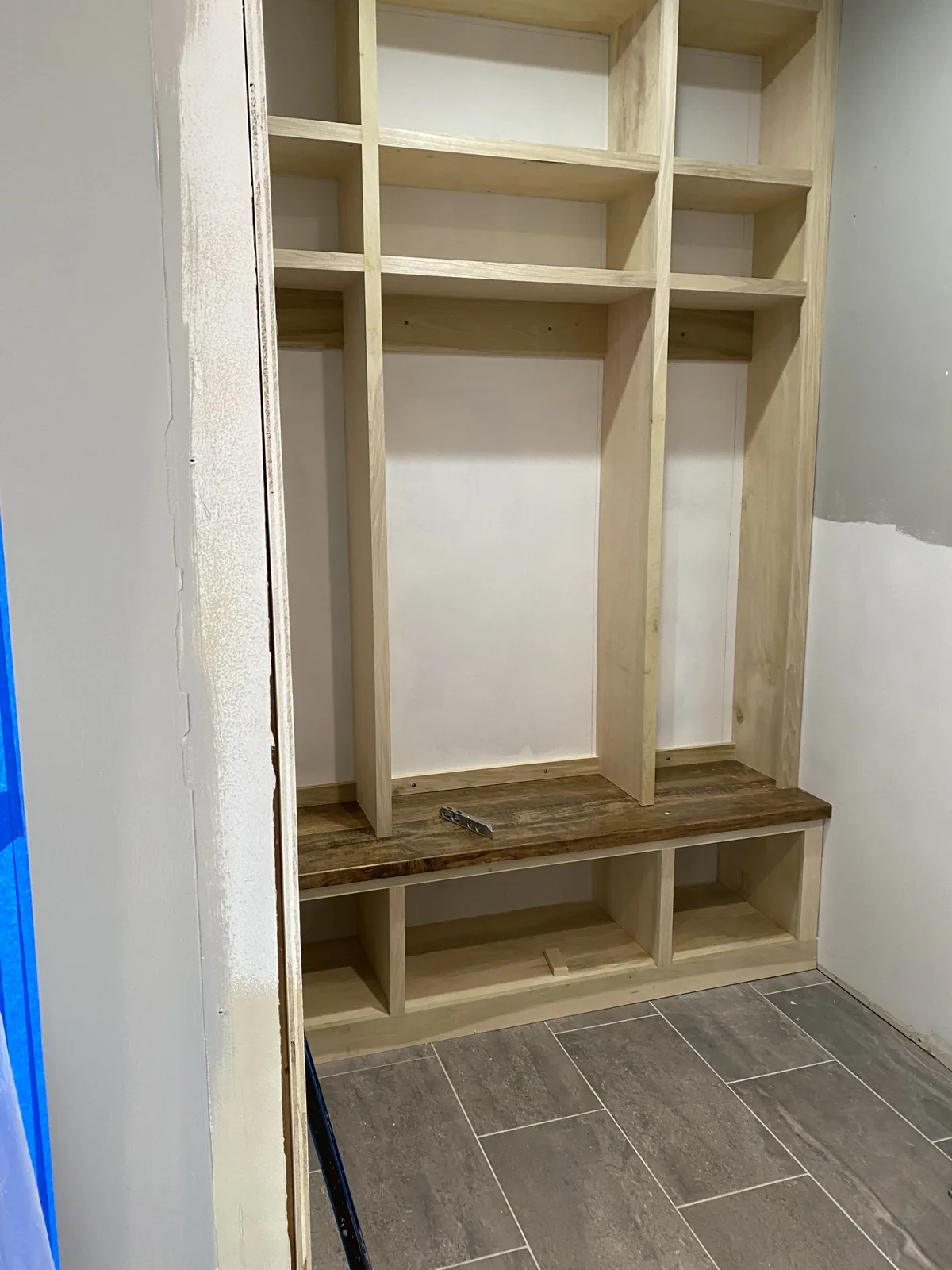 Mudroom remodel in Kansas City, MO during construction: the built-in locker carcass in raw wood with the walnut bench top already fitted over open shoe cubbies