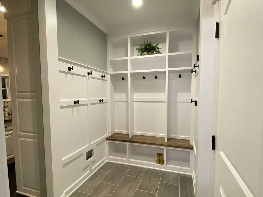Mudroom remodel in Kansas City, MO with white built-in lockers, black hooks, and a walnut bench top