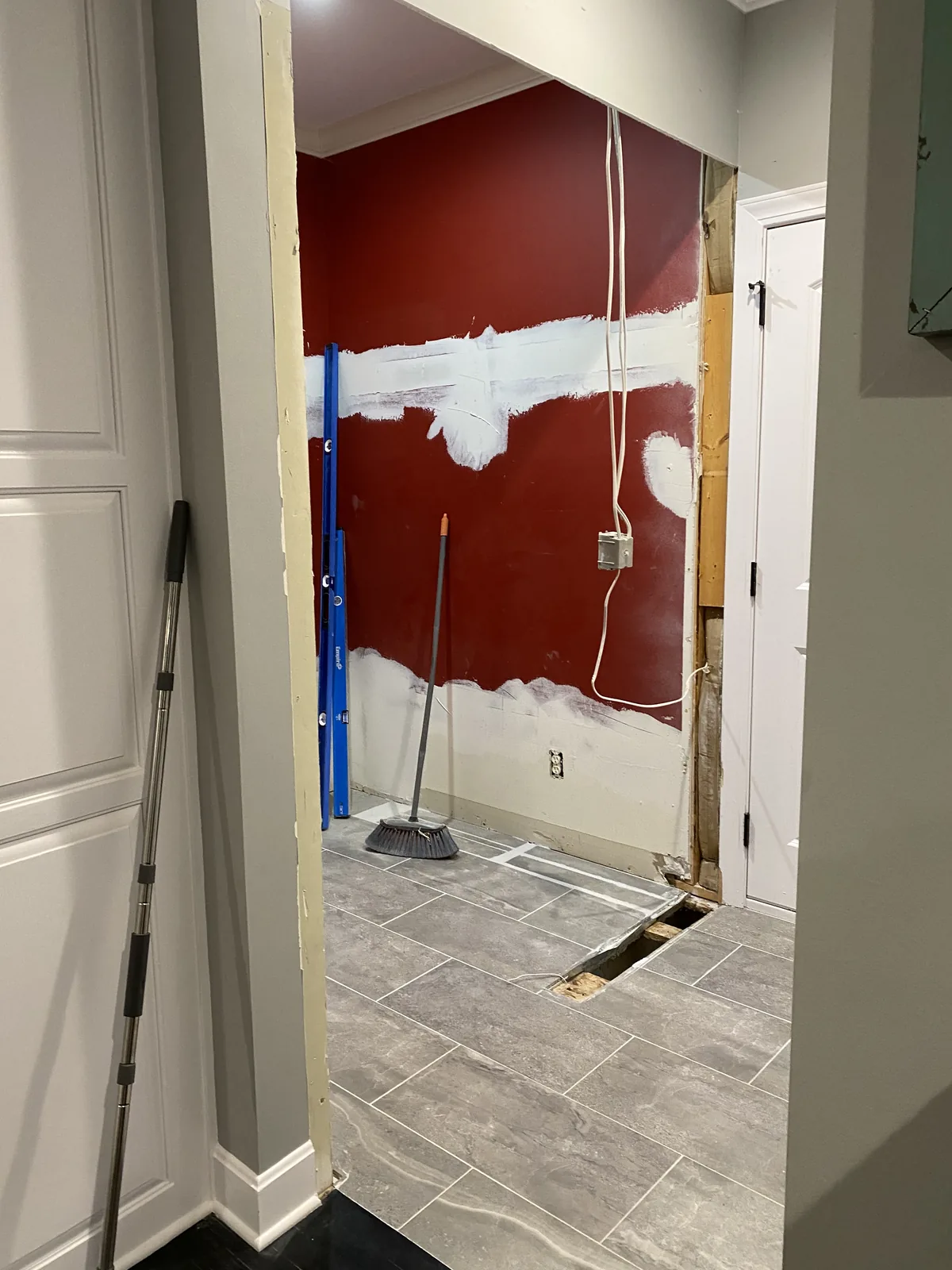 Mudroom remodel in Kansas City, MO: the finished rough opening looking into the old red room, with patched drywall where circuits were rerouted and a strip of bare subfloor where the wall stood