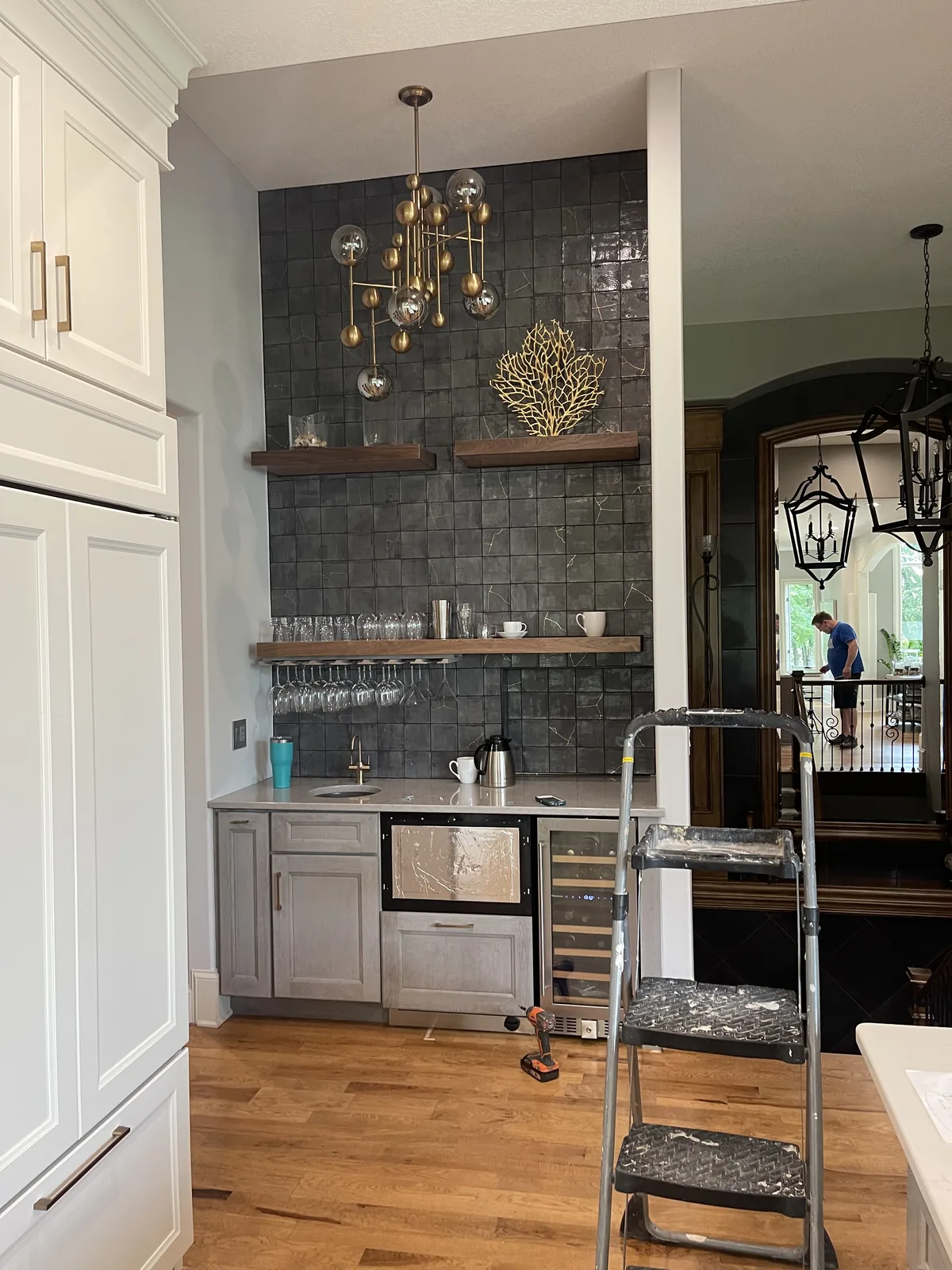 Kitchen renovation in Loch Lloyd, MO: the bar alcove during finishing, with dark glazed tile, walnut floating shelves, and an undercounter wine refrigerator