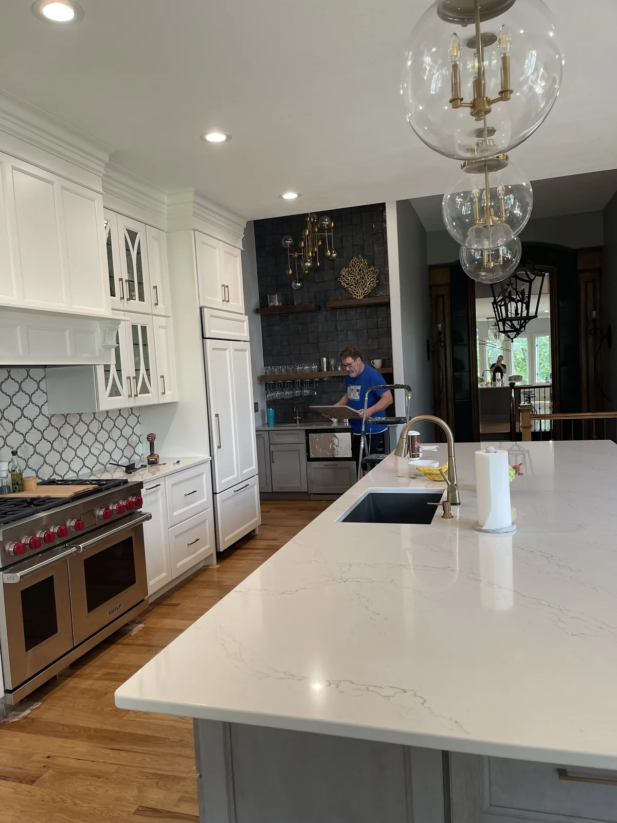 Kitchen renovation in Loch Lloyd, MO: quartz island with undermount sink, range under the arabesque backsplash, and the bar alcove beyond