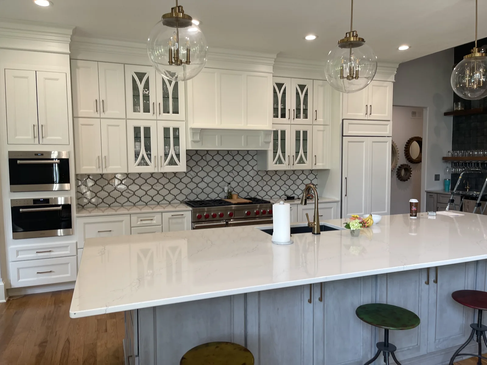Kitchen renovation in Loch Lloyd, MO with arabesque tile backsplash, arched glass-front upper cabinetry, and a quartz island with a grey-washed base