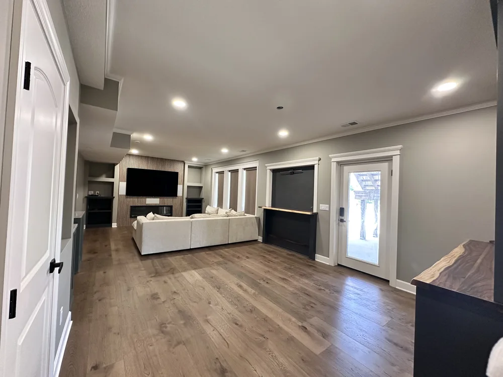 Basement renovation in Lone Jack, MO with wood slat media wall, fireplace, and walkout door to the pool