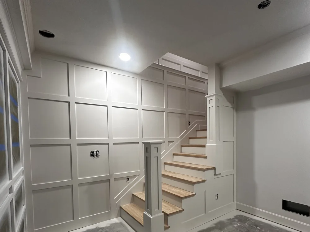 Basement renovation in Lone Jack, MO with custom white wainscoting on the stairway